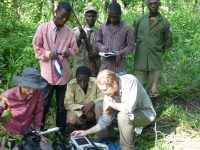 Picture of scientists gathering data in a rain forest. Armed guards in the background